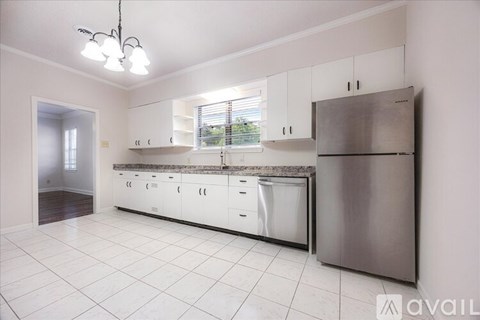 A kitchen with white cabinets and a stainless steel refrigerator.