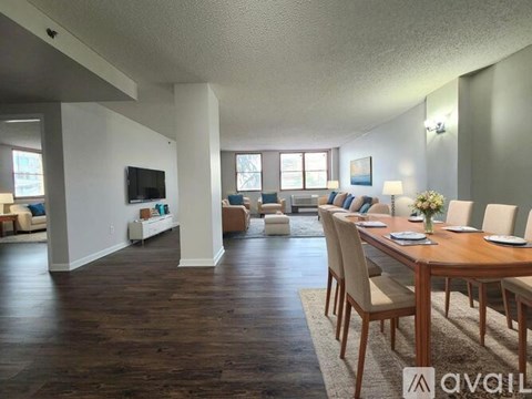 A living room with a wooden floor and a long table with chairs.