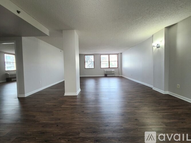 A spacious room with wooden floors and white walls.