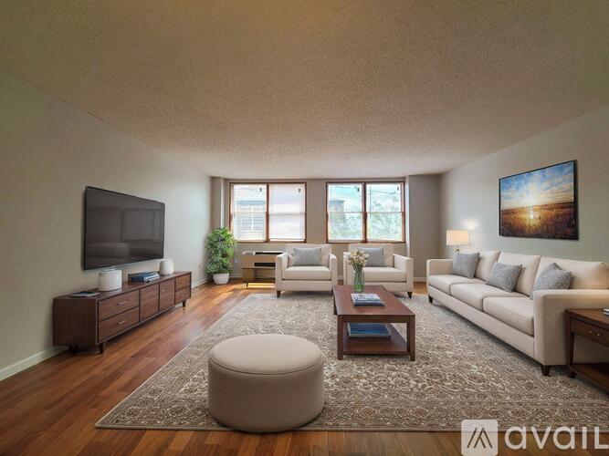 A living room with a flat screen TV, a white sofa, a coffee table, and a rug.