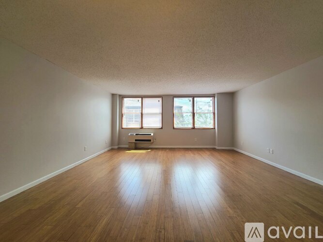 A room with wooden floors and a window with blinds.