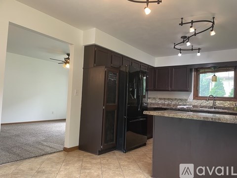 A kitchen with a black refrigerator and a countertop with a window.