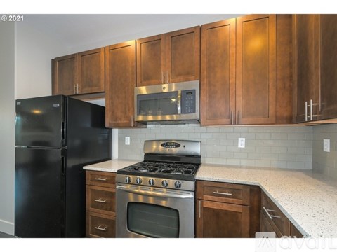 A kitchen with wooden cabinets and a black refrigerator.
