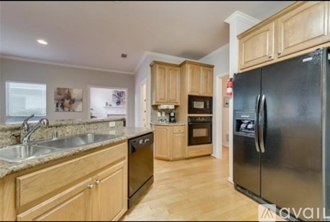 A kitchen with wooden cabinets and a black refrigerator.