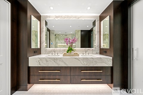 A bathroom with a marble countertop and wooden cabinets.