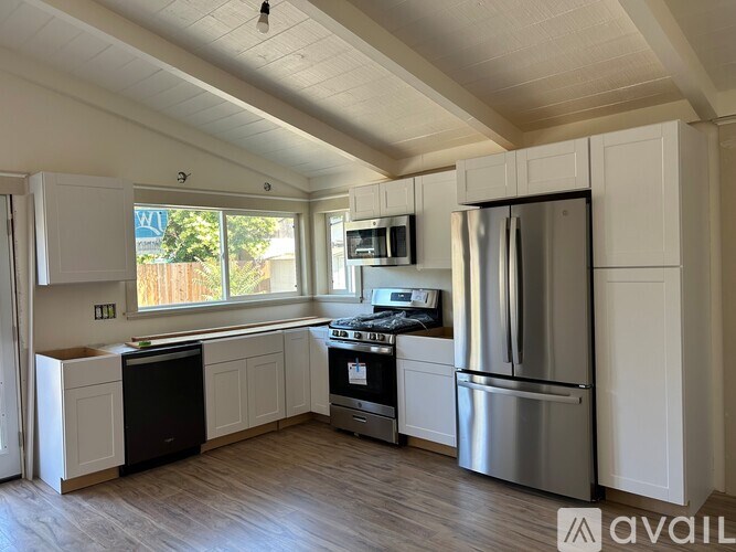 A kitchen with white cabinets and a stainless steel refrigerator.