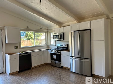 A kitchen with white cabinets and a stainless steel refrigerator.
