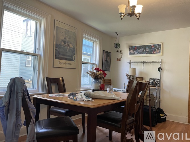 A dining room with a table set for two and a painting on the wall.