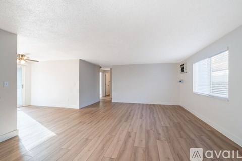 A spacious room with wooden flooring and white walls.