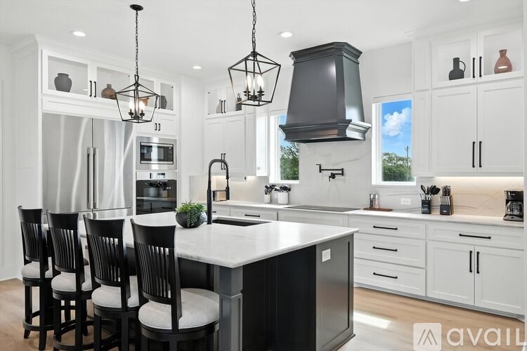 A modern kitchen with a large island and black chairs.