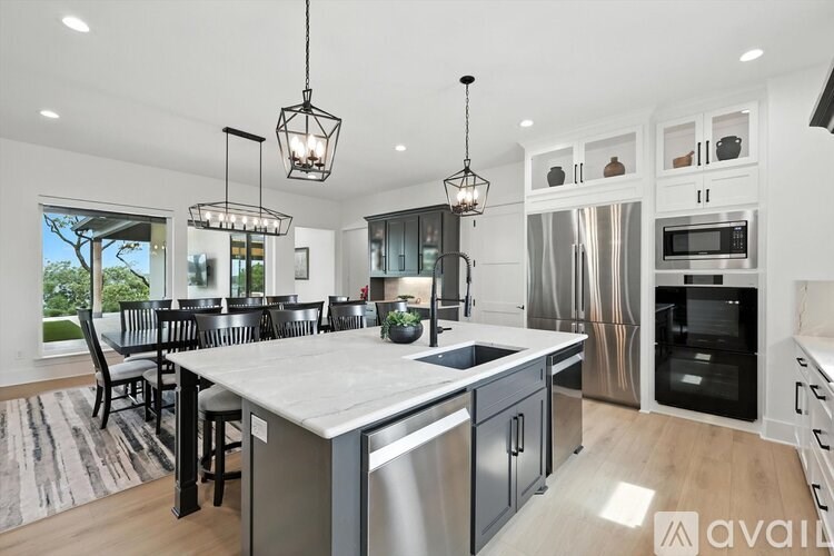 A modern kitchen with a large island and pendant lights.