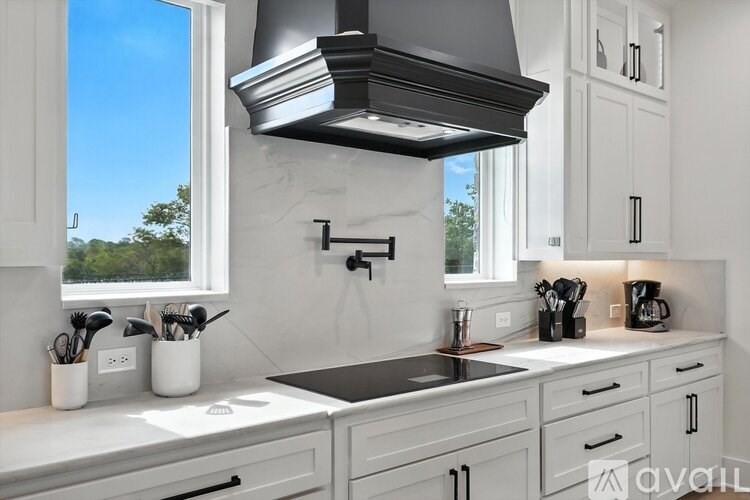 A kitchen with a black range hood above the sink.