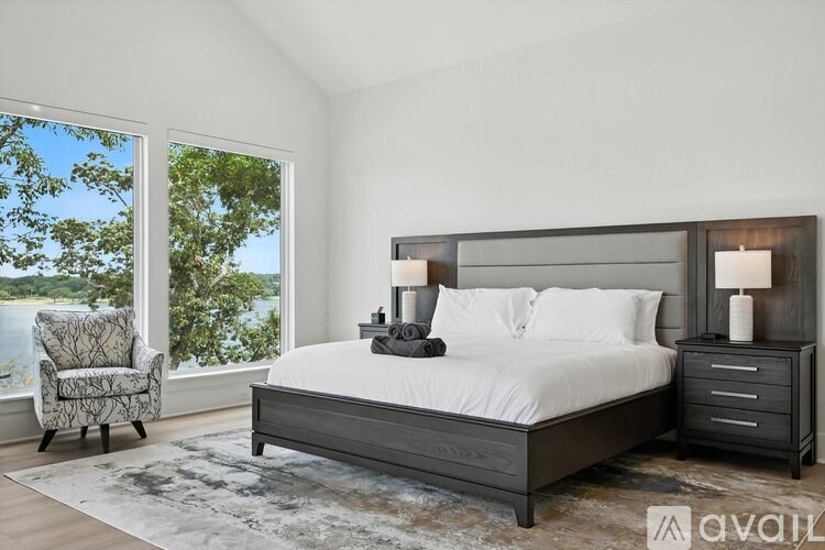 A bedroom with a large bed, a chair, and a view of the water.