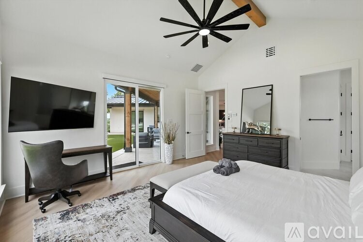A bedroom with a large bed, a television, and a ceiling fan.