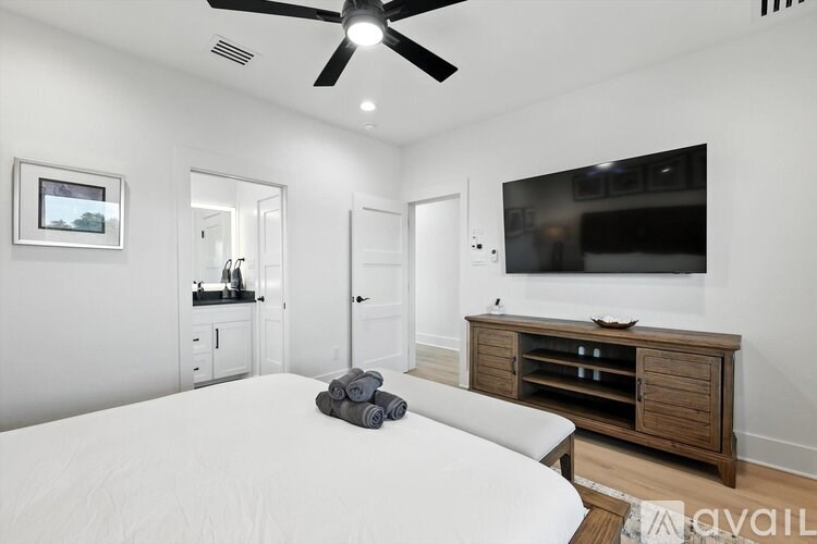 A bedroom with a bed, a dresser, and a ceiling fan.
