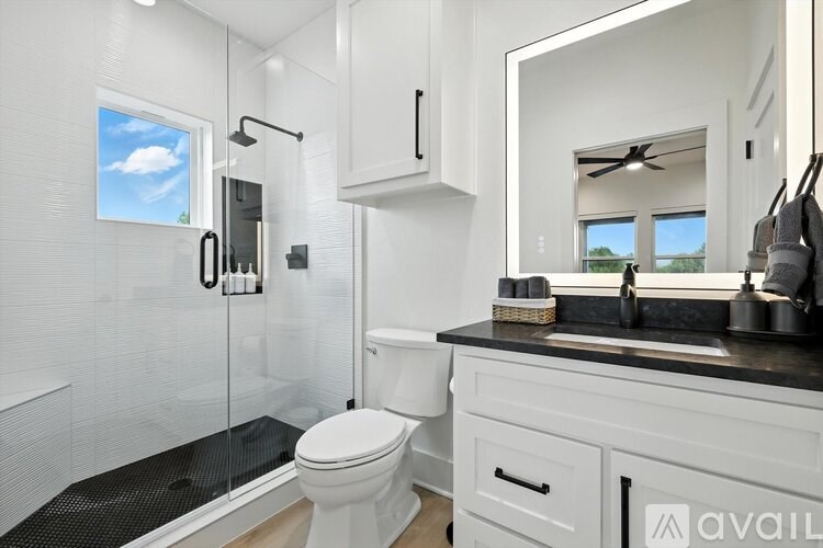 A bathroom with a toilet, sink, and mirror.