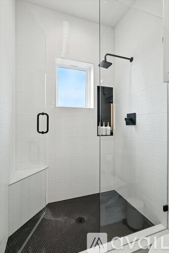 A modern bathroom with a glass shower stall and a window.