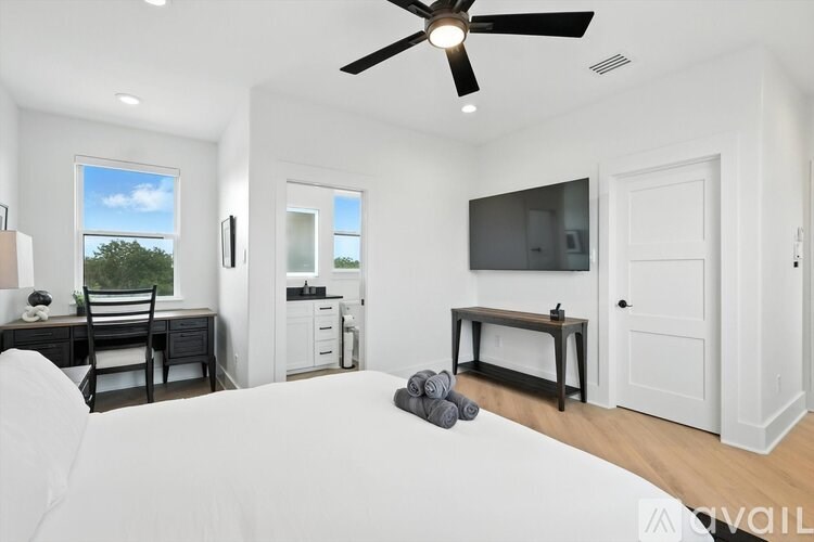 A white couch sits in a bright room with a ceiling fan and a window showing a tree and sky.