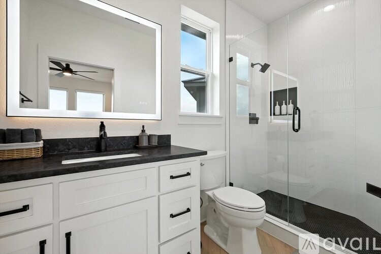 A bathroom with a mirror, sink, toilet and shower.