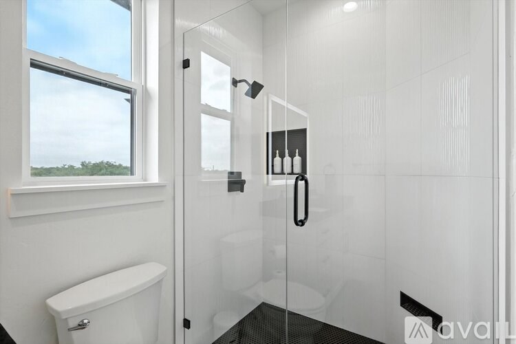 A white bathroom with a glass shower door and a toilet.