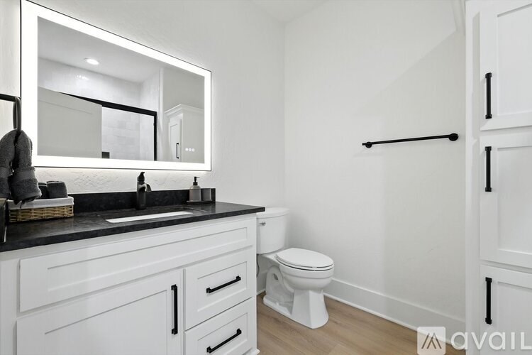 A white bathroom with a sink, mirror, and toilet.