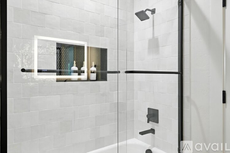 A modern bathroom with a glass shower door and a white tiled wall.