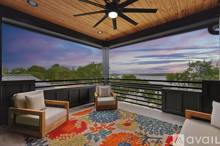 A balcony with two chairs and a rug in the foreground.