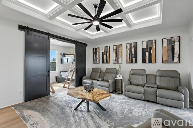 A modern living room with a black ceiling fan and grey sofas.