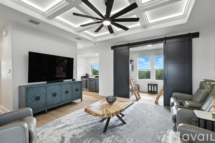 A modern living room with a ceiling fan and a flat screen TV.
