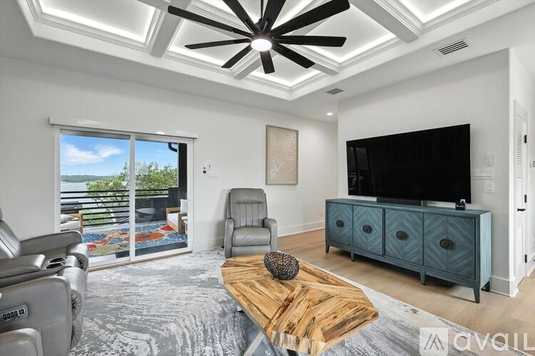 A modern living room with a flat screen TV and a ceiling fan.
