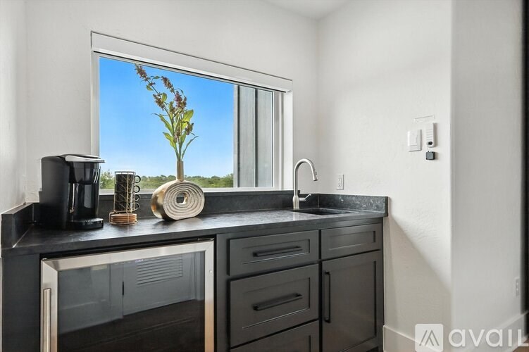 A kitchen with a black countertop and a window showing a tree.