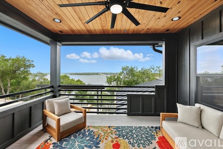 A balcony with a ceiling fan, a chair, and a couch with a view of the water.