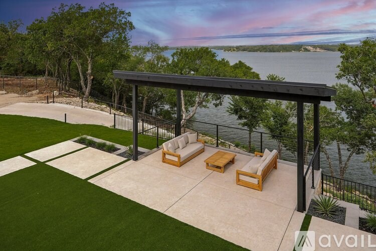 A patio with a table and chairs overlooking a body of water.