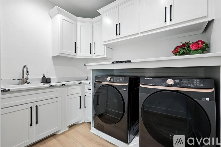 A modern kitchen with white cabinets and black appliances.