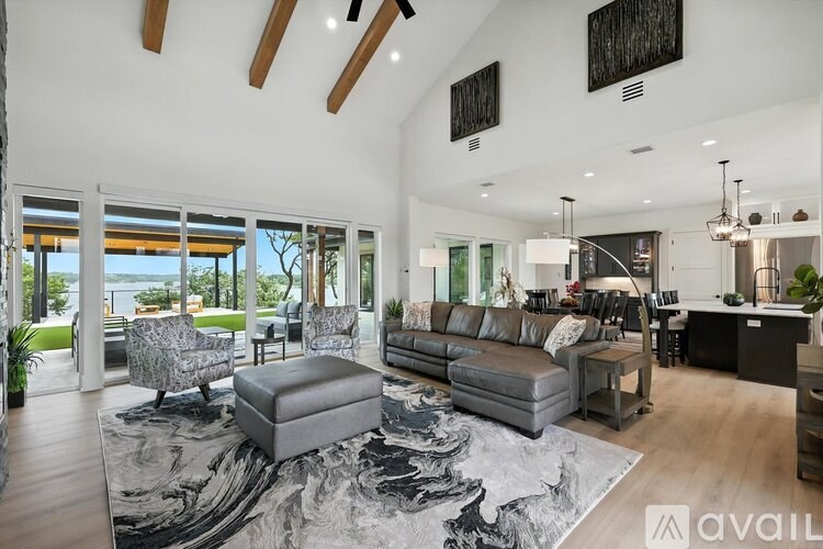 A modern living room with a large grey rug and a grey ottoman.