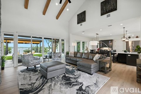 A modern living room with a large grey rug and a grey ottoman.