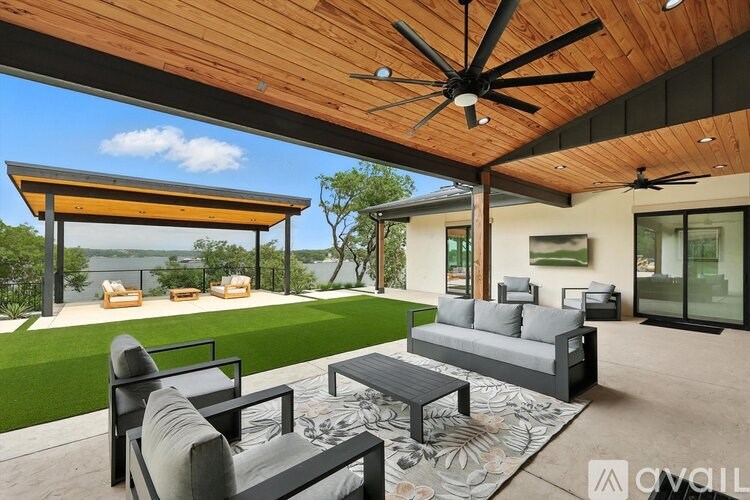 A modern outdoor living space with a wooden ceiling fan and a glass wall.