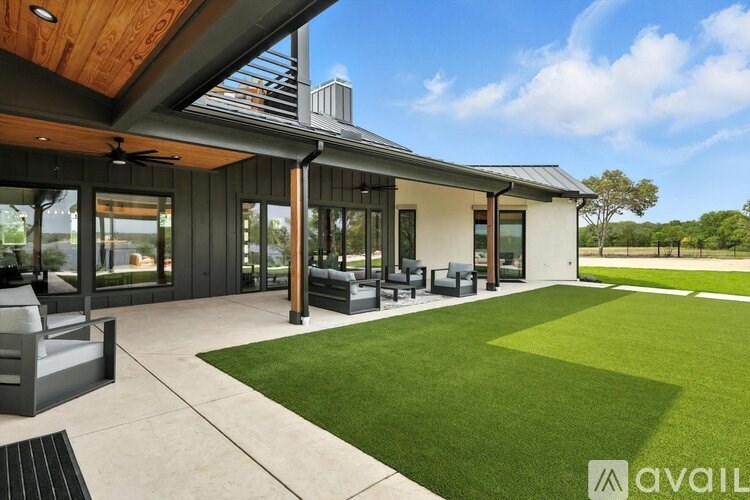 A modern house with a large backyard and a patio area.