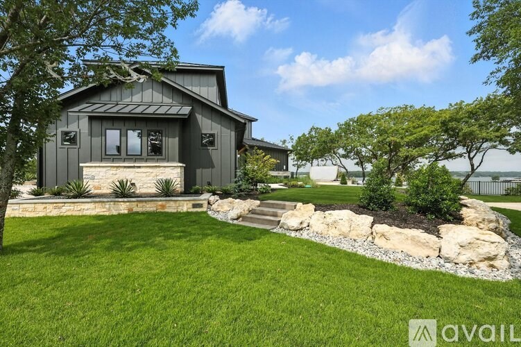A modern house with a stone wall and a well-manicured lawn.