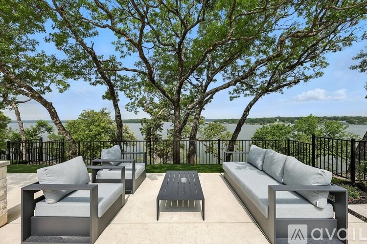 A patio with a table and chairs overlooking a body of water.