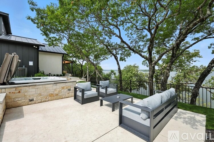 A patio area with a hot tub, chairs, and a table.