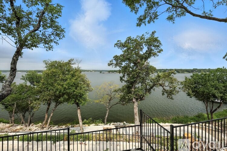 A view of a lake from a balcony with trees in the foreground.