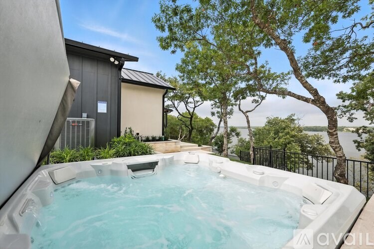 A hot tub is surrounded by a black fence and trees.