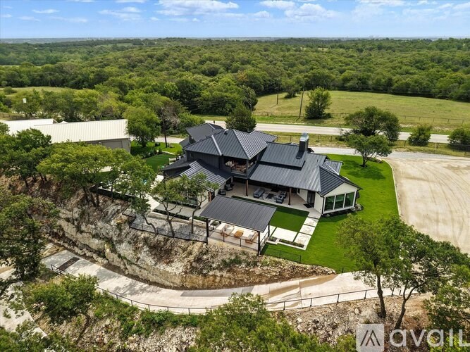 A modern house with a black roof is surrounded by greenery.
