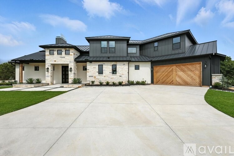 A modern house with a black roof and a large driveway.