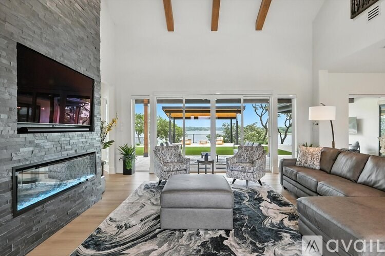 A modern living room with a stone fireplace and a large window overlooking the ocean.