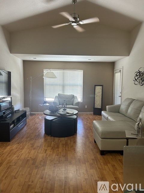 A living room with a black leather sofa and a wooden floor.