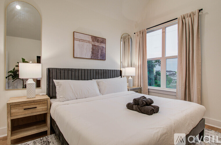 A bedroom with a large bed, a nightstand with a lamp, and a framed picture on the wall.