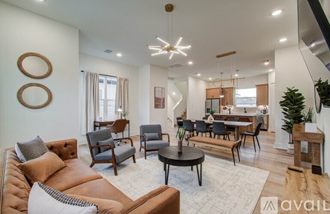 A living room with a brown leather couch and a round wooden table.