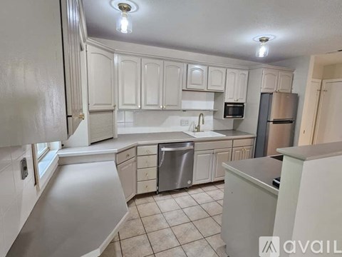 A kitchen with white cabinets and a tiled floor.